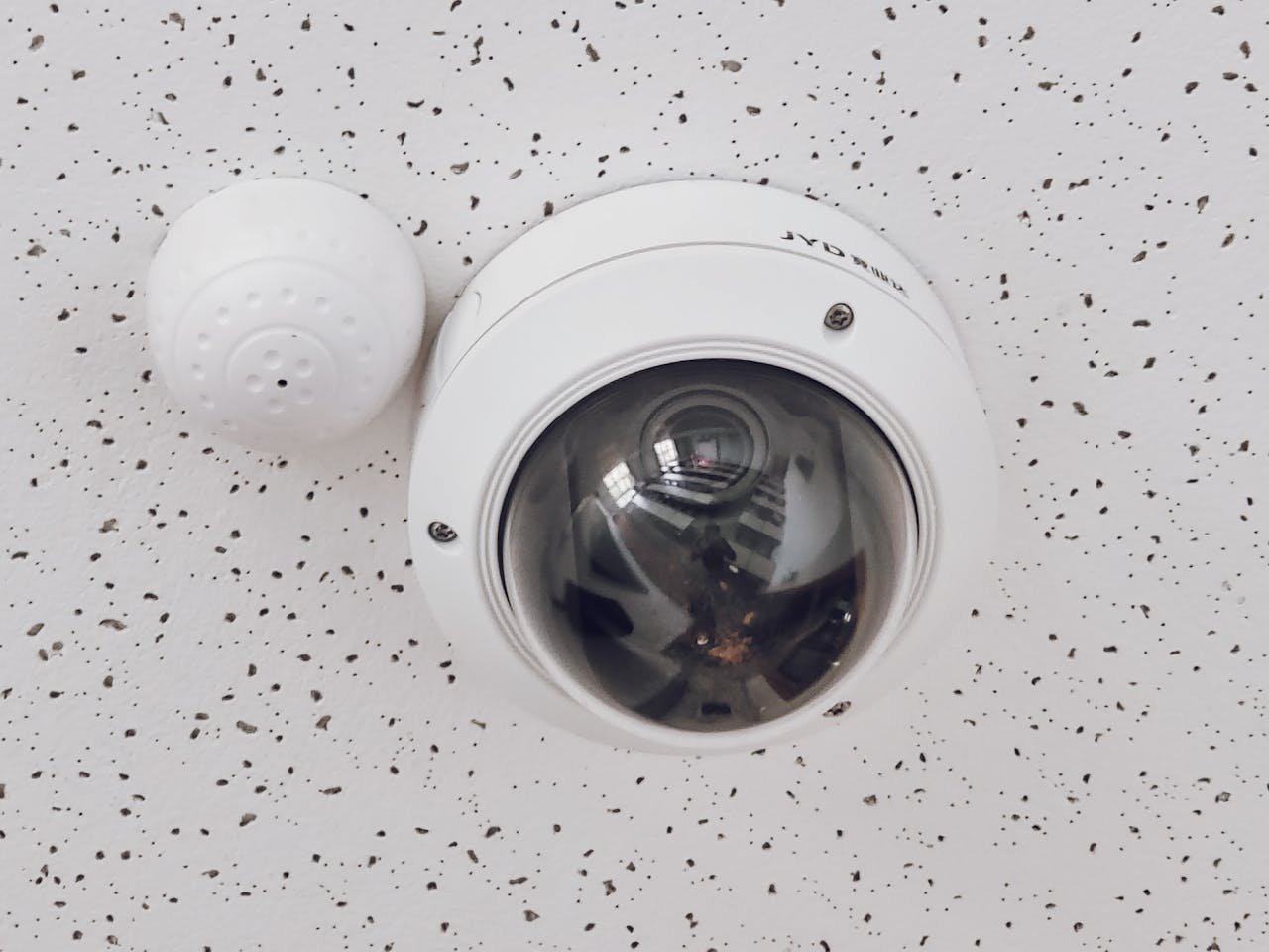 home-hero Close-up of a round dome surveillance camera installed on a speckled ceiling for security monitoring.